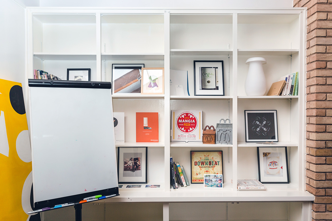 A white wall of shelves with books and picture frames in an office